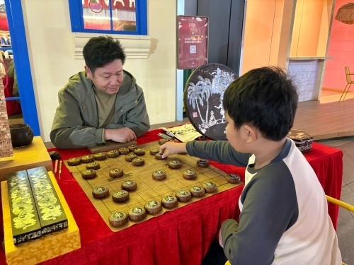 柯秋楓與市民下椰雕象棋。人民網(wǎng) 陳葉欣攝