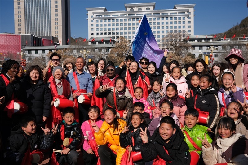 中外青年學(xué)子在安塞文化廣場(chǎng)觀看陜北腰鼓和大秧歌表演后合影留念，大家踏著鼓點(diǎn)共舞，翻飛的紅綢與躍動(dòng)的身影交織，在黃土地廣場(chǎng)上繪出一幅生動(dòng)的陜北民俗互動(dòng)畫(huà)卷