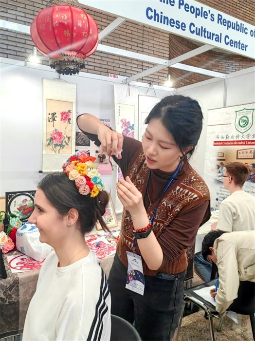 展覽正值羅馬尼亞迎春花節(jié)，國(guó)際中文教師志愿者潘婧穎向游客們介紹了國(guó)家非物質(zhì)文化遺產(chǎn)——福建泉州的簪花文化。布加勒斯特大學(xué)孔子學(xué)院供圖。