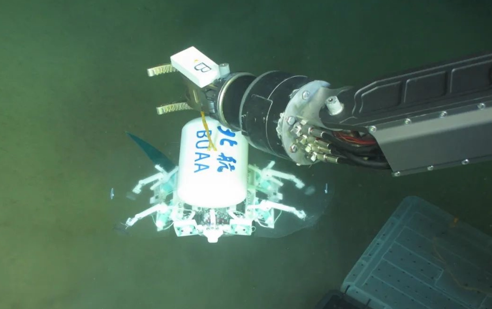 科研人員利用機械臂將北航深海小型機器人投于馬里亞納海溝。校方供圖