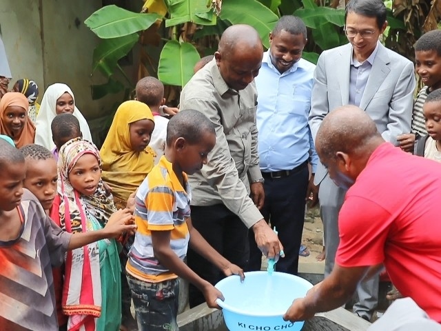 在日前舉行的安全供水工程揭牌儀式上，當(dāng)?shù)匦∨笥言诠┧c接水。 施亮攝