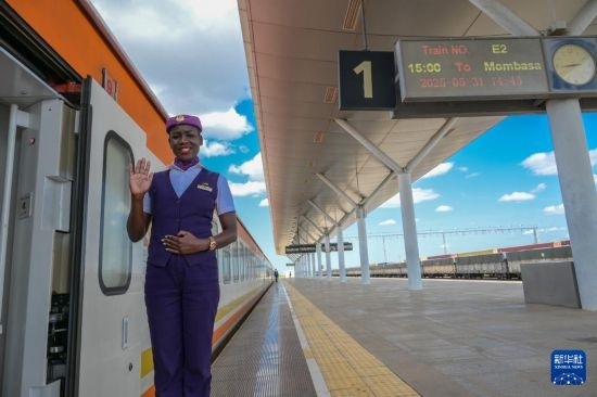5月31日，在蒙內鐵路內羅畢站，一名乘務員在即將開往蒙巴薩的E2次列車旁等候乘客。新華社記者 楊光 攝